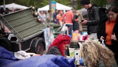 Lady-with-bright-red-hair-squats-down-to-look-at-things-at-the-flea-market