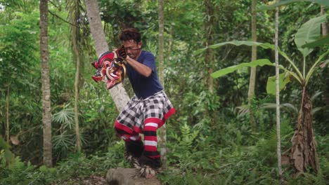 Un-Artista-Balinés-Realiza-La-épica-Danza-De-Máscaras-Barong-Bangkung,-Narrando-La-Rica-Mitología-Cultural-De-Bali-Sobre-El-Tronco-De-Un-árbol-En-El-Bosque-Del-Pueblo.