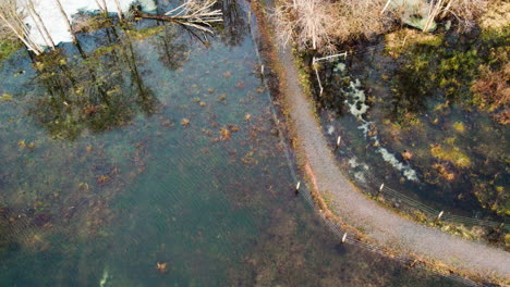 Curved-Rural-Road-Surrounded-by-Flooded-Land-With-Reflection,-Winter-Season,-Aerial