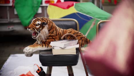 Tiger-cuddly-toy-animal-lying-on-bar-stool-for-sale-at-flea-market-close-up