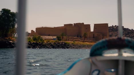 Boat-view-of-the-Philae-temple-complex-island-in-Aswan-Dam-and-Lake-Nasser,-Egypt