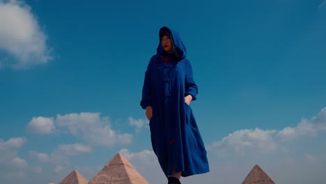 Mysterious-female-traveler-walks-in-desert-at-Giza-pyramids-in-traditional-Egyptian-outfit