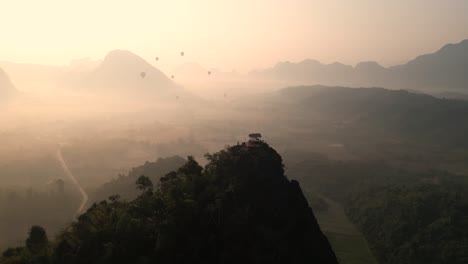sunrise-drone-shot-of-cliffs-and-hot-air-balloons-in-Vang-Vieng,-the-adventure-capital-of-Laos