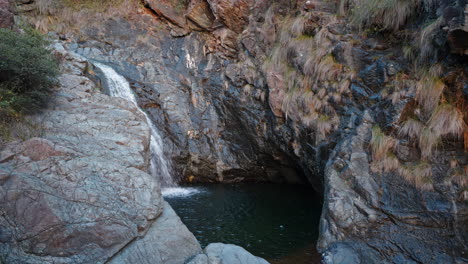 Una-Cascada-Aislada-Cae-En-Una-Serena-Piscina-De-Roca-Rodeada-De-Escarpados-Acantilados