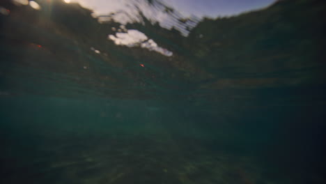 Underwater-view-of-breaking-wave-with-mystical-light-on-surface