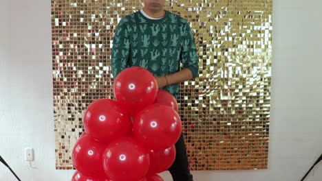 Man-tying-party-balloons-together,-red-balloon-party-decor