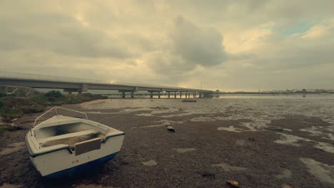 A-time-lapse-captures-an-old-boat-resting-on-the-sandy-shores-of-a-tranquil-coastal-area,-embodying-the-essence-of-nostalgia-and-maritime-heritage