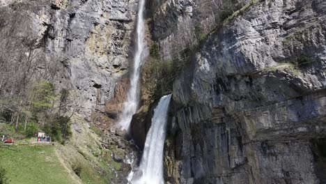 Experience-the-beauty-of-Seerenbach-Falls-as-it-cascades-into-the-tranquil-waters-of-Walensee,-Switzerland,-captured-in-drone-footage