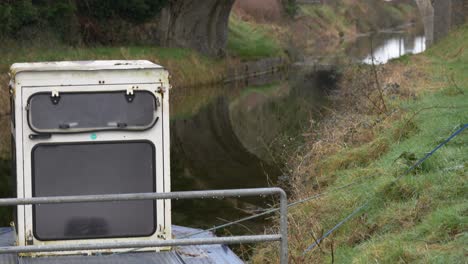 Rusty-service-boat-moored-on-the-Grand-Canal,-County-Kildare,-with-grassy-banks