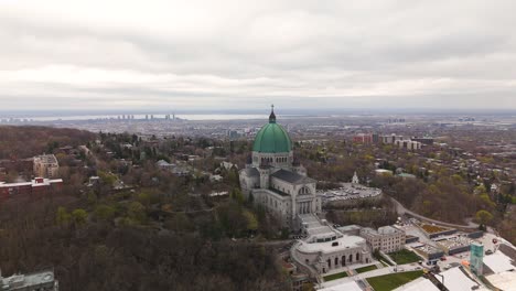 Aerial-view-of-Saint-Joseph's-Oratory-of-Mount-Royal,-with-Montreal-cityscape-at-distance-during-a-cloudy-day