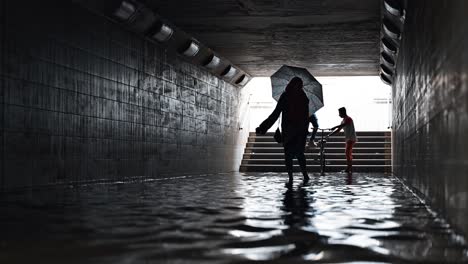 Residents-crossing-a-waterlogged-pedestrian-underpass-after-the-rain-hit-the-UAE-on-May-02,-2024