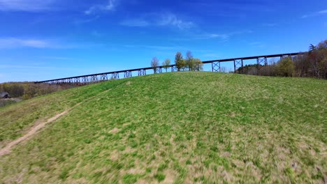 A-low-angle-aerial-view-with-an-FPV-drone-flying-towards-the-Moodna-Viaduct-in-Salisbury-Mills,-NY-on-a-sunny-day