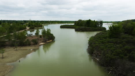Shelby-farms-park,-lush-greenery-surrounding-a-tranquil-lake,-cloudy-day,-aerial-view