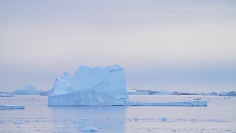 Hermoso-Iceberg-Al-Atardecer-En-La-Antártida,-Grandes-Icebergs-Masivos-Con-Formas-Sorprendentes-Y-Formación-De-Hielo,-Paisaje-Marino-Al-Amanecer-Con-Cielo-Naranja-En-El-Paisaje-Invernal-En-La-Península-Antártica