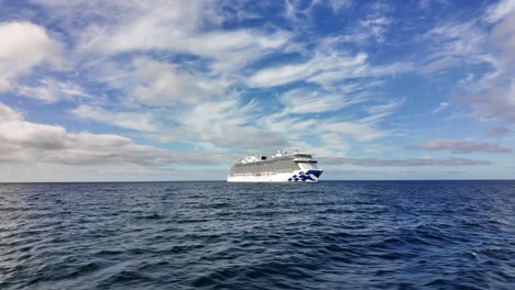 Cruise-ship-sailing-on-the-ocean-under-a-sunny-sky,-viewed-from-a-small-boat