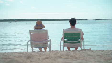 Pareja-Sentada-En-Sillas-En-La-Playa-Mirando-Al-Mar-Lento