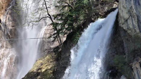 Twin-cascades-of-Seerenbach-Falls-weave-a-misty-veil-in-Amden,-a-serene-display-of-nature's-force-in-the-Swiss-landscape