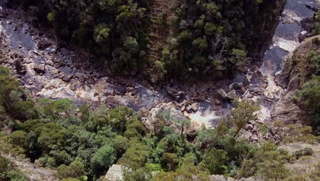 Aerial-shot-of-water-stream-flowing-though-the-stones-in-Leven-Canyon-in-Tasmania,-Australia