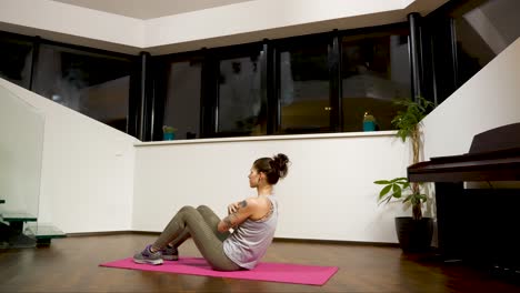 Woman-exercising-with-sit-ups-at-home,-evening-indoor-setting,-health-and-wellness-focus,-wide-shot
