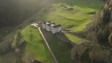 Luftaufnahme-Eines-Alten-Gebäudes-In-Einem-Schweizer-Bergtal-Im-Sommer-Bei-Sonnenuntergang