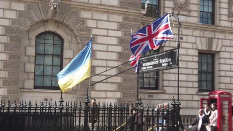 Slow-motion-of-the-Union-Jack,-EU-and-Ukraine-flags-tried-to-the-Westminster-underground-station