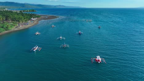 Aerial-drone-flight-over-coastline-of-Sarangani-with-beach-and-traditional-bangka,-fishing-boats-in-south-Philippines