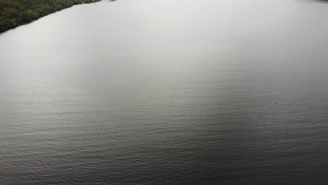 Vista-Aérea-Sobre-Las-Tranquilas-Aguas-Del-Lago-Ness-Con-Nubes-Encima