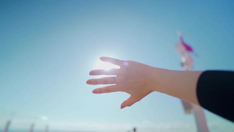 Woman-hand-raised-toward-the-sun-in-the-sky