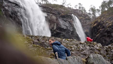 Besucher-Machen-Während-Der-Wanderung-Eine-Pause-Vor-Dem-Hesjedalsfossen-Wasserfall,-Norwegen,-Filmische-Enthüllung