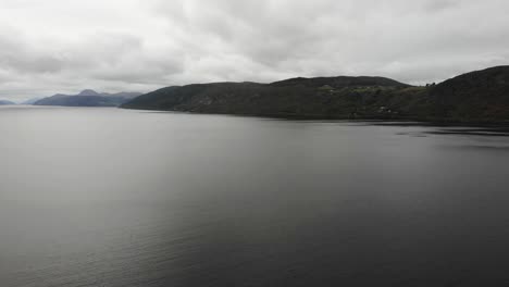 Luftaufnahme-über-Dem-Ruhigen-Wasser-Von-Loch-Ness-Mit-Berglandschaft-Im-Hintergrund