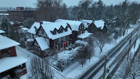 Schneebedeckte-Häuser-Im-Tudor-Stil-Mit-Steilen-Satteldächern,-Gelegen-Entlang-Einer-Schneebedeckten-Straße-Mit-Kahlen-Bäumen