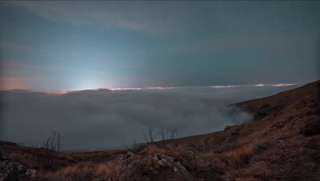 Nighttime-clouds-rolling-over-hills-under-a-starry-sky,-moonrise-illuminating-the-scene,-timelapse