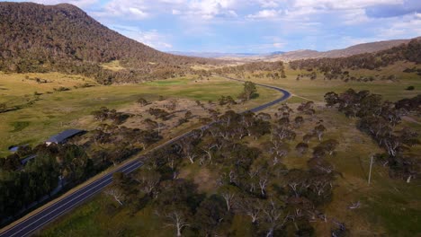 Drone-view-of-country-farm-house-and-road-with-overcast-sky-in-Crackenback,-New-South-Wales,-Australia