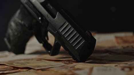 Close-up-of-a-handgun-standing-on-a-lot-of-cash-with-flashing-police-lights-in-the-background