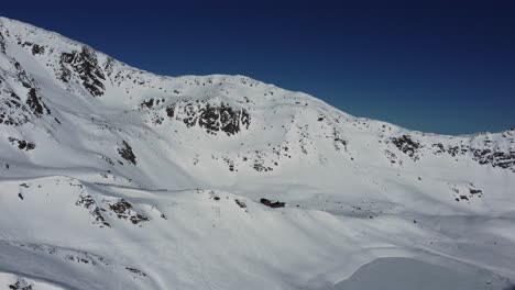 Abgelegene-Hütte-In-Weißen,-Schneebedeckten-Bergen-In-Den-Alpen,-Luftaufnahme