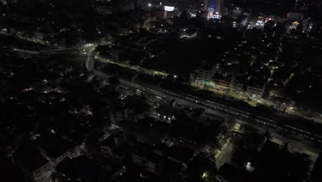 Toma-Aérea-De-Drones-De-La-Ciudad-De-Chennai-Con-Luces,-Edificios,-Vista-Nocturna-Con-Tráfico-Y-Tren-Pasando-Por-Vías-Férreas