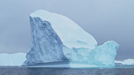 Gran-Iceberg-En-El-Paisaje-Invernal-De-La-Antártida,-Increíble-Formación-De-Hielo-De-Enormes-Icebergs-Azules-En-El-Paisaje-Marino-De-La-Península-Antártica-Con-Agua-De-Mar