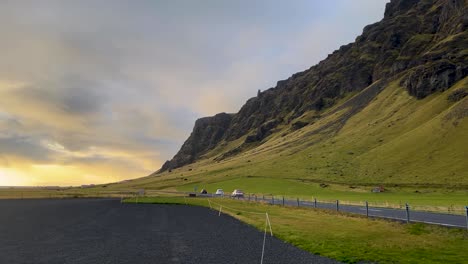 Cars-drive-toward-cloudy-sunset-on-mountainside-road-in-rural-Iceland