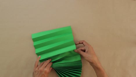 Piece-of-paper,-green-in-color,-folded-elegantly-into-the-shape-of-a-fan