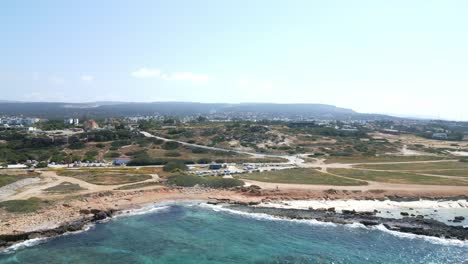 Agios-georgios-beach-in-cyprus,-clear-blue-waters-along-rocky-shores,-aerial-view