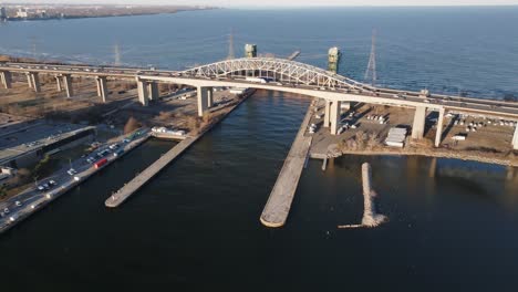 Skyway-Bridge-Mit-Verkehr-über-Ruhigem-Wasser-Bei-Sonnenuntergang-In-Hamilton,-Ontario,-Warmes-Licht,-Luftaufnahme