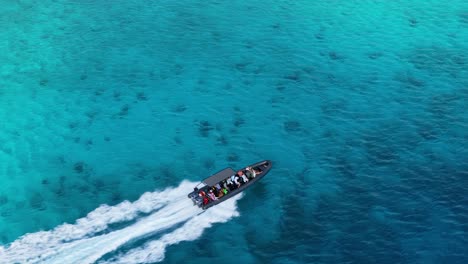 Aerial-high-angle-overview-follows-canopy-on-boat-gliding-across-sandy-benthic-ocean-water