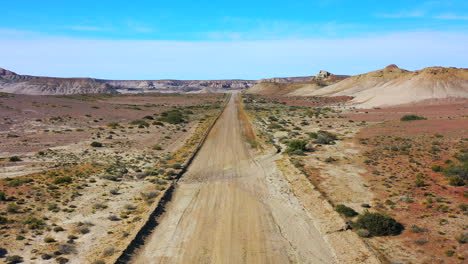 Toma-Aérea-Pista-Polvorienta-Desierto-Paisaje-Asombroso-Sarmiento-Argentina-Cielo-Azul-Cañón