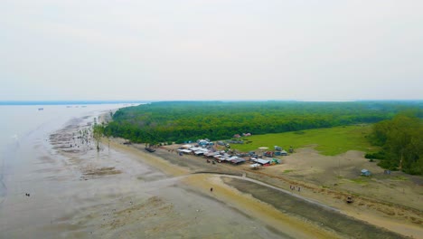Small-market-along-forest-at-Kuakata-sea-beach-in-Bangladesh,-aerial-rising-establisher-after-storm
