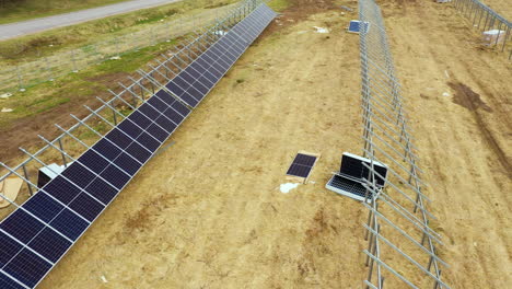 Newly-constructed-developing-solar-farm-with-bare-metal-lattice-frames,-aerial