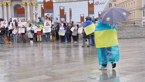 Kind-In-Ukrainische-Blau-gelbe-Flagge-Gehüllt-Geht-über-Verregneten-Boden-In-Der-Hauptstadt