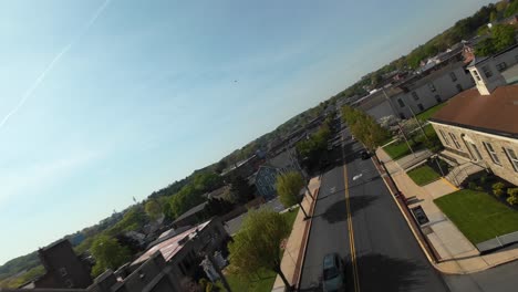 FPV-Drone-flight-over-small-town-in-american-city-during-sunny-day-with-church-and-driving-cars-on-junction