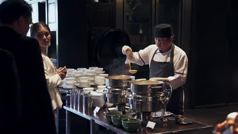 Chef-Revolviendo-Sopa-En-Ollas-Grandes-En-La-Animada-Cocina-De-Un-Restaurante