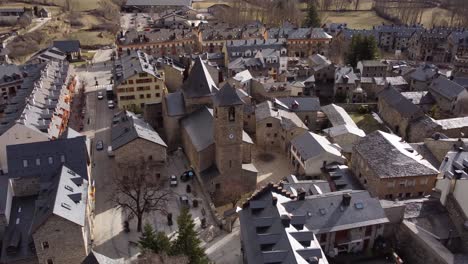 Aerial-view-dolly-out-of-the-Church-of-Santa-Maria-in-Benasque,-Romanesque-Lombard-architecture,-in-the-Aragonese-Pyrenees,-Spain