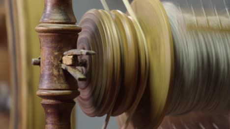 Full-frame-close-up:-Yarn-bobbin-spins-on-traditional-spinning-wheel